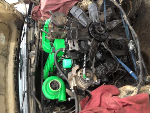 1995 Ford Bronco - Close-up view of an engine bay a prominent green turbocharger and various mechanical parts.
