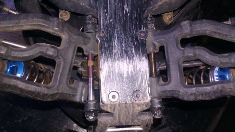 1996 Ford Bronco - This image shows the suspension system of a remote control car, blue shock absorbers and a scratched metal chassis.
