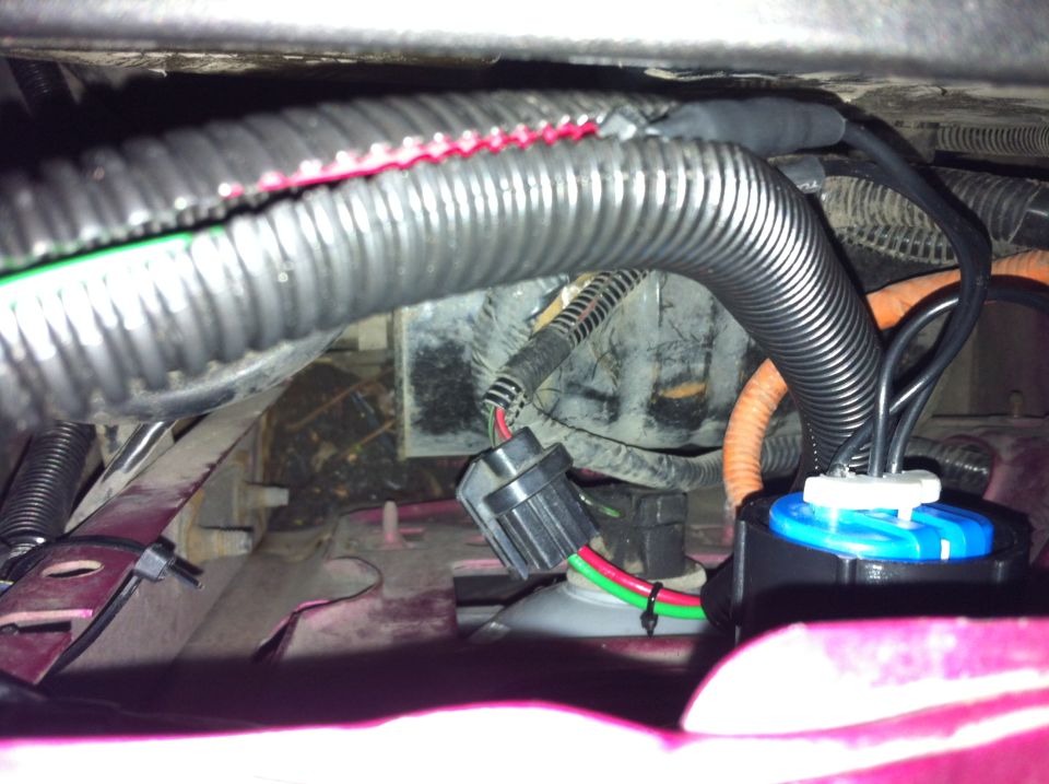 Close-up of vehicle wiring harness with black corrugated tubing and connectors