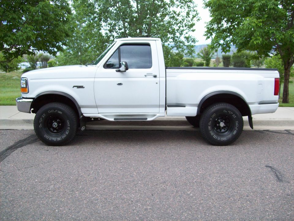 Side view of a white pickup truck with black wheels and running boards
