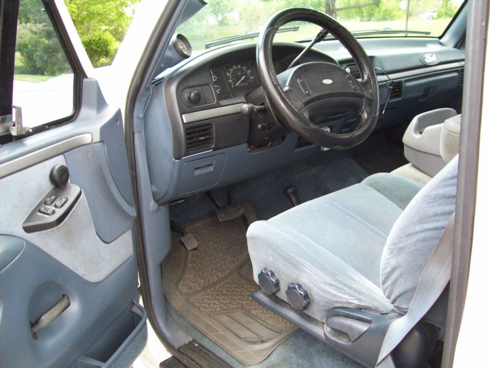 Interior of a 1993 Ford F-150 showing the dashboard, steering wheel, driver's seat, and door panel