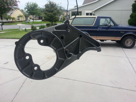 1994 Ford Bronco - A gray metal part hangs in front of a blue 1994 Ford Bronco parked in a driveway.