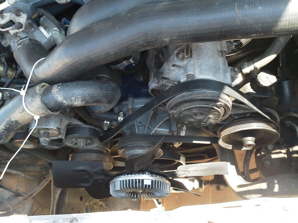 Engine bay showing serpentine belt system, pulleys, and fan