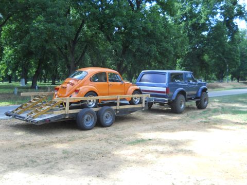 1992 Ford Bronco - Blue 1992 Ford Bronco tows a trailer carrying an orange Volkswagen Beetle.