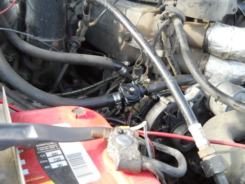 1992 Ford Bronco - Close-up view of engine components, including a red battery and various hoses.