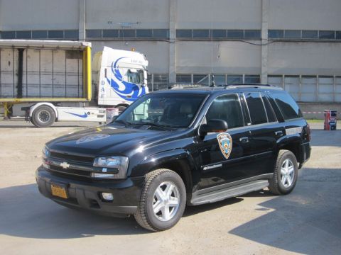1991 Ford Crown Victoria - Black police SUV with a shield on the door is parked in front of a building.