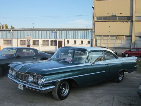1991 Ford Crown Victoria - A classic two-tone green and white coupe is parked outside a building with another car beside it.