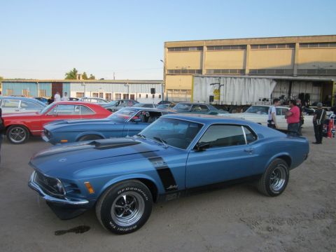 1991 Ford Crown Victoria - A blue 1970 Ford Mustang Boss 302 is parked at an outdoor event with other vehicles.