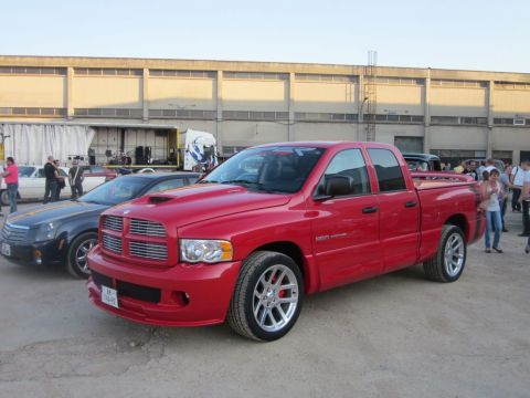 1991 Ford Crown Victoria - A red Dodge Ram SRT-10 pickup truck is parked next to a black Cadillac sedan.