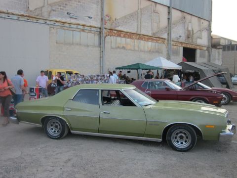1991 Ford Crown Victoria - A green sedan is parked next to other vehicles and tents at an outdoor event.