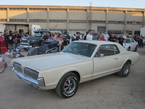 1991 Ford Crown Victoria - A classic Mercury Cougar is displayed at an outdoor event with other vehicles and spectators.