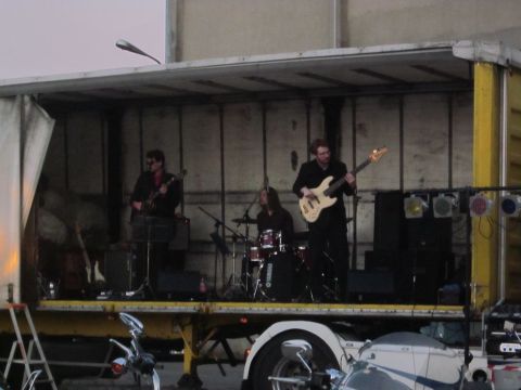 1991 Ford Crown Victoria - A band plays music on a trailer set up as a stage, with a motorcycle visible in front of the trailer.