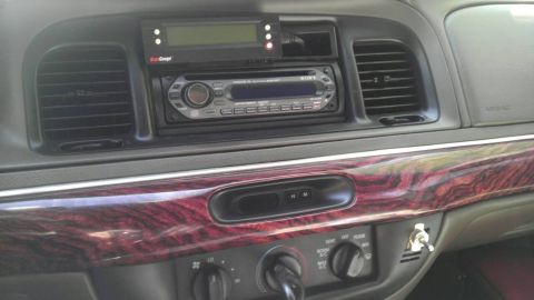 2000 Mercury Grand Marquis - Interior shot of a car's dashboard an aftermarket stereo and wood grain trim.