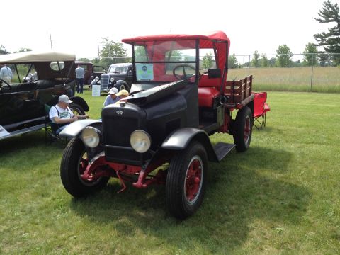 1988 Ford Bronco - A vintage truck with a red canvas top and wooden bed is displayed outdoors.