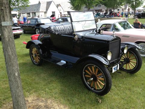1988 Ford Bronco - A classic black touring car is displayed at an outdoor event with other vehicles and attendees.
