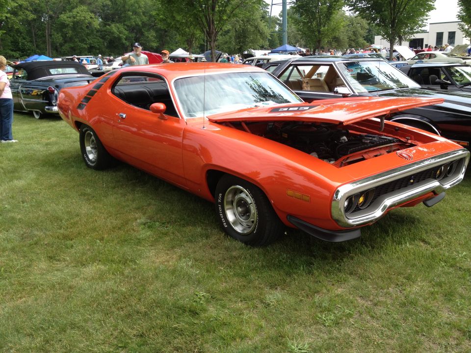 Orange 1971 Plymouth Road Runner with hood open, parked on grass at a car show
