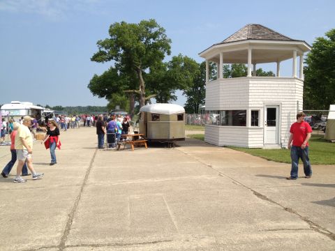 1988 Ford Bronco - A trailer sits beside a white structure with a gazebo top, surrounded by people at an outdoor gathering.