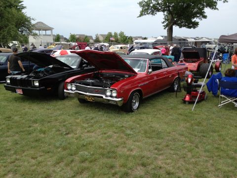 1988 Ford Bronco - A red convertible is displayed with its hood up at an outdoor car show, parked next to a black vehicle.