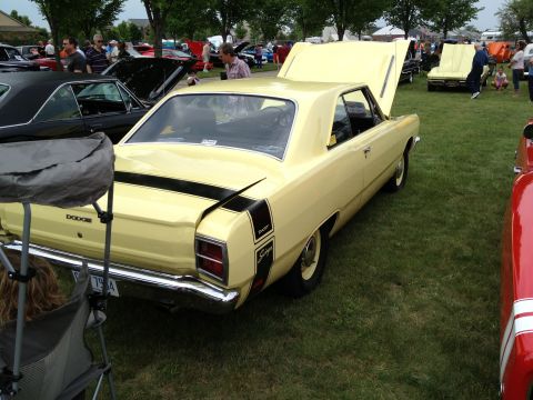 1988 Ford Bronco - A yellow 1970 Dodge Dart Swinger is displayed at a car show, its hood and trunk open.