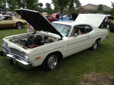 1988 Ford Bronco - A white coupe is displayed with its hood open at an outdoor car show, with other vehicles parked around it on the grass.