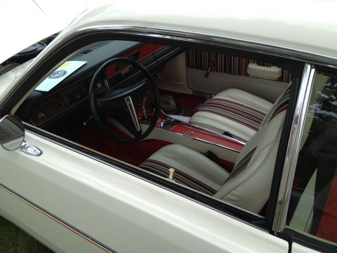 1988 Ford Bronco - The interior of a white car features striped cloth seats and a wood-grain dashboard and center console.