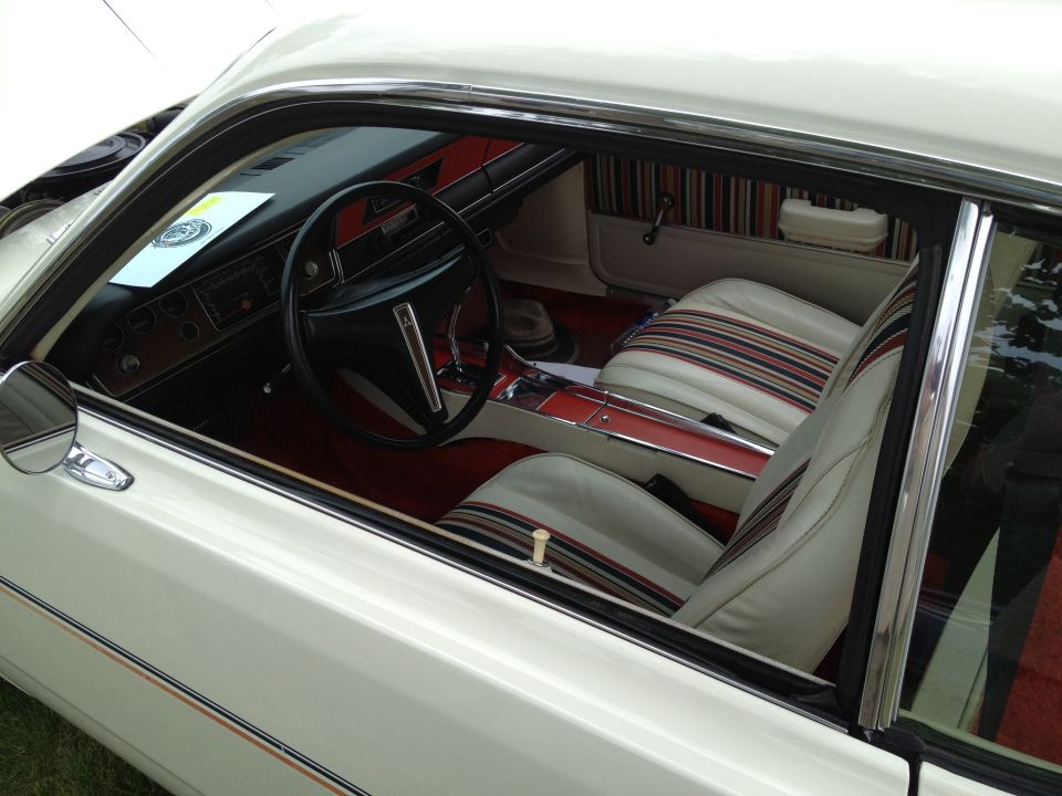 White classic coupe interior with red carpet and striped vinyl bucket seats