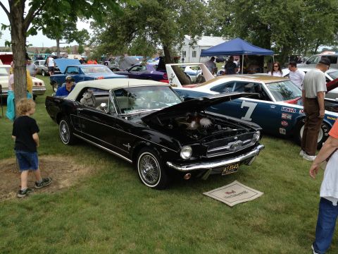1988 Ford Bronco - A black 1965 Ford Mustang convertible is displayed with its hood open at an outdoor car show.