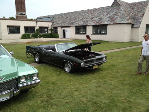 1988 Ford Bronco - A dark green convertible is displayed on a grassy lawn with its hood open, next to another vehicle.
