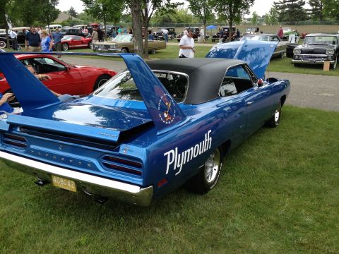 1988 Ford Bronco - A classic Plymouth Superbird is displayed on a grassy field with other vehicles and attendees in the background.