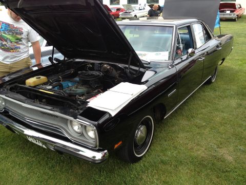 1988 Ford Bronco - Black 1969 Plymouth GTX on display with hood open, other vehicles in background.