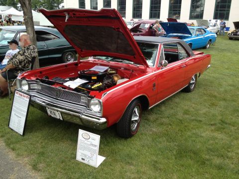 1988 Ford Bronco - A red 1967 Dodge Dart is displayed with its hood open at an outdoor car show.