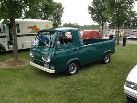 1988 Ford Bronco - A green pickup truck is parked on a grassy field next to a white delivery truck.