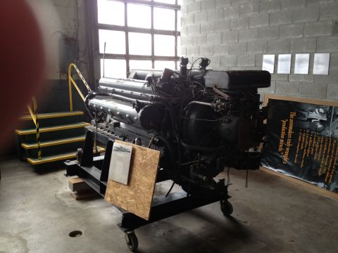 1988 Ford Bronco - A V12 engine is displayed on a stand, with informational text nearby.