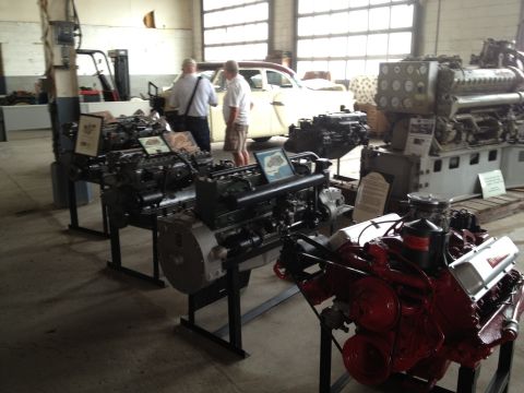 1988 Ford Bronco - Multiple engines are displayed indoors at the Packard Proving Grounds Yearly Car show, with a classic car visible in the background.