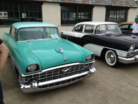 1988 Ford Bronco - Two classic Packard Clipper models, one turquoise and white, the other black and white, are parked side-by-side at an outdoor car show.