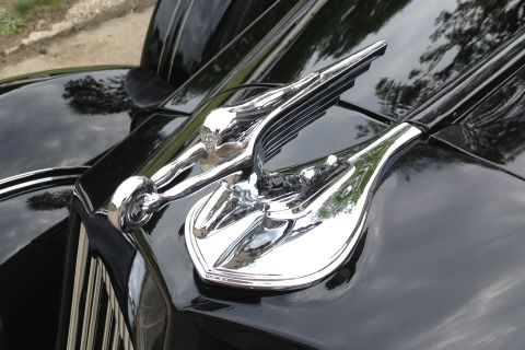 1988 Ford Bronco - Close-up of a shiny chrome hood ornament on a black vehicle.
