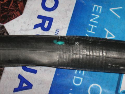 1994 Ford Bronco - A close-up view of a damaged bicycle inner tube with sealant escaping from a puncture.