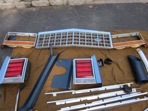 2001 Ford Crown Victoria - Collection of car parts including a Ford grille and taillights are displayed on a blanket.