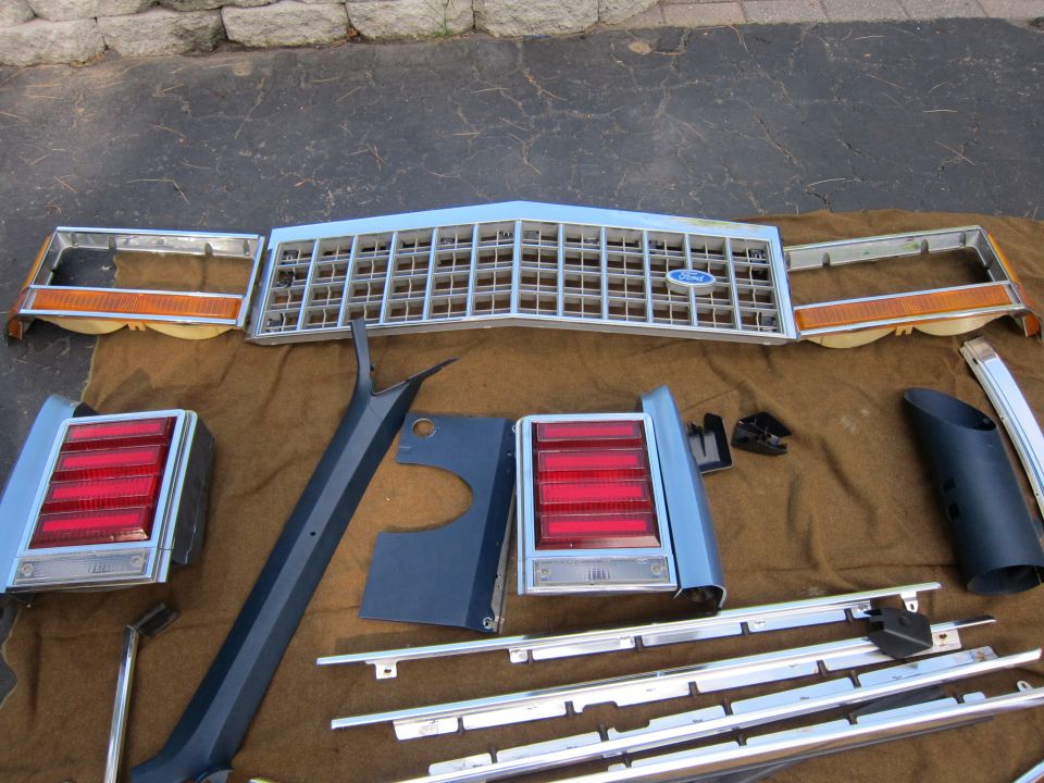 Ford grille, two taillights, and trim pieces laid out on a brown blanket