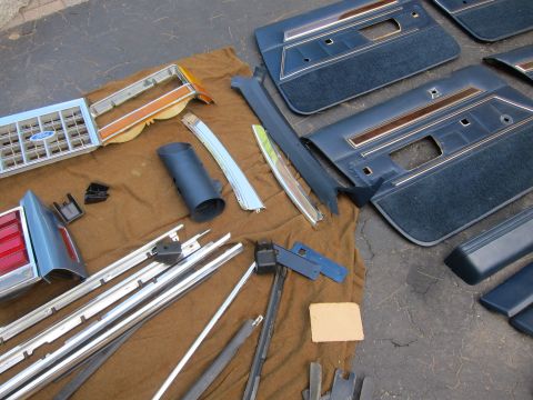 2001 Ford Crown Victoria - Various car parts, including a Ford grille and interior door panels, are displayed on a cloth surface.