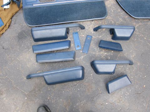 2001 Ford Crown Victoria - Various blue interior car door panels and trim pieces are arranged on a dark, cracked asphalt surface.