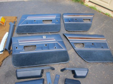 2001 Ford Crown Victoria - A collection of blue interior door panels and trim pieces are displayed on a paved surface.