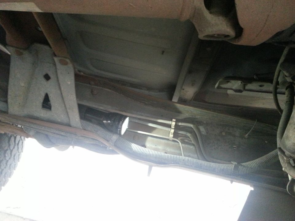 Underside of vehicle showing frame, fuel tank, filter and lines