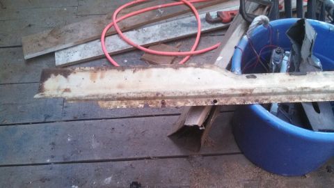 1979 Ford Bronco - A rusted metal rocker panel is shown resting on wooden planks, with a blue tub and other parts in the background.