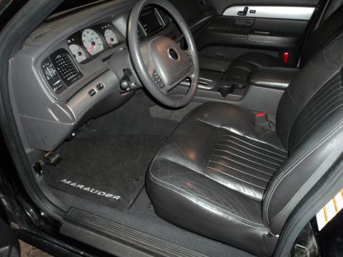 2004 Mercury Grand Marquis - The interior of a car shows black leather seats and the dashboard with gauges and steering wheel.