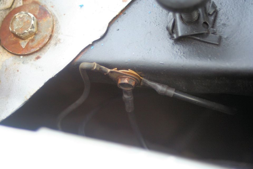 Close-up of a rusty bolt connecting wires on a vehicle's chassis