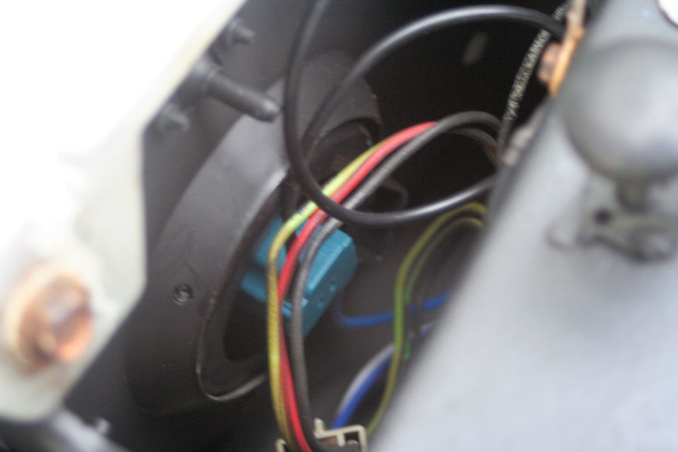 Close-up of headlight wiring with red, yellow, and black wires connected to a blue component