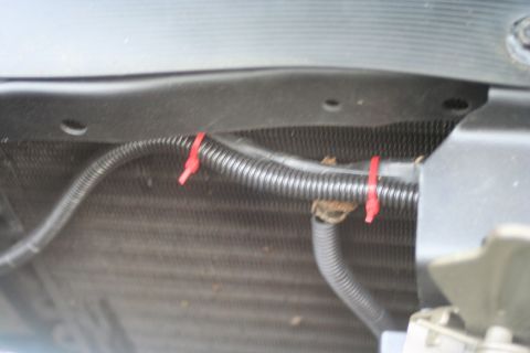 1976 Ford Ranchero - Close-up view of corrugated tubing and red zip ties attached to a vehicle's front grille area.