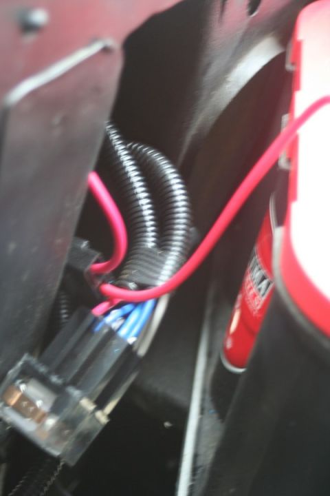 1976 Ford Ranchero - Detail of automotive wiring and a red cylindrical object, possibly a fluid reservoir or battery terminal cover.