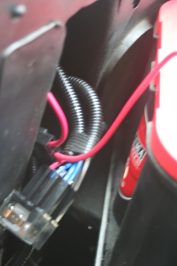 Close-up of a red canister and a black wiring harness with red, blue, and white wires
